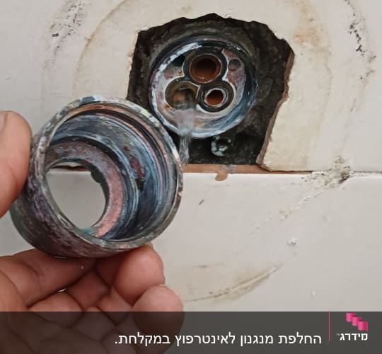יד מחזיקה חלק צנרת מתכת עם חור בקיר